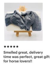 Load image into Gallery viewer, A grey and white handmade vegan soap featuring a highly detailed relief of two horses nuzzling heads, displayed on a wooden easel against a whimsical farmhouse decor background.
