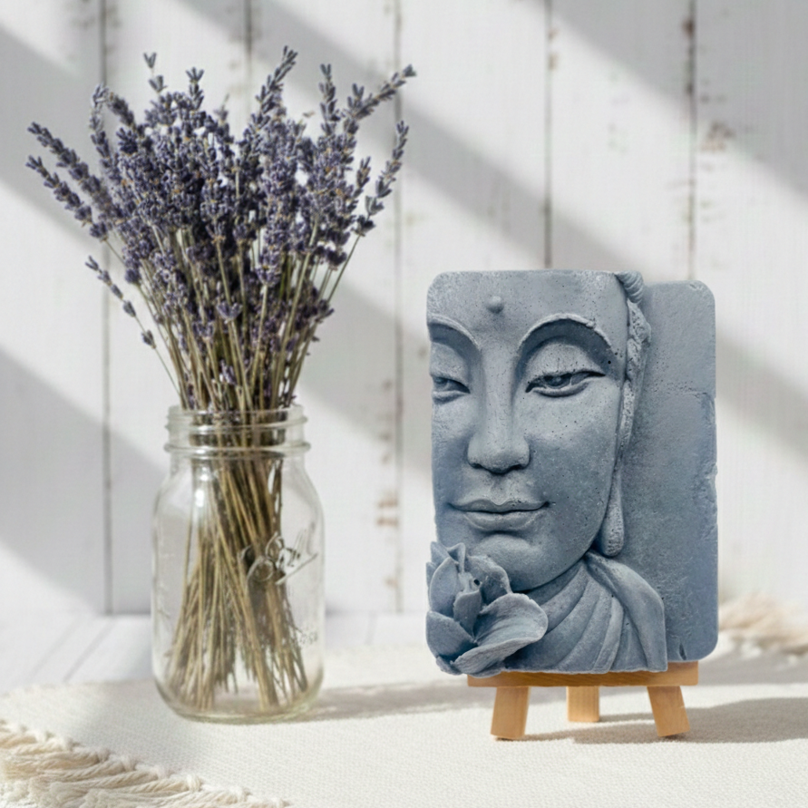 handmade vegan soap featuring a detailed 3D relief of a serene Buddha face with a lotus flower, displayed on a wooden easel against a whimsical farmhouse decor background.