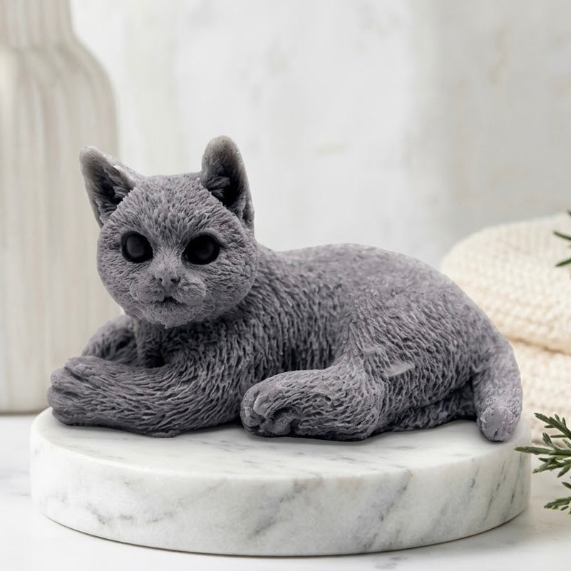 Realistic charcoal grey cat-shaped soap on a marble plinth with towels.