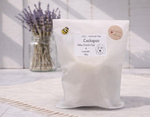 Load image into Gallery viewer, Bag of Cockapoo Yellow French Clay &amp; Lavender soap with a jar of lavender flowers in the background.
