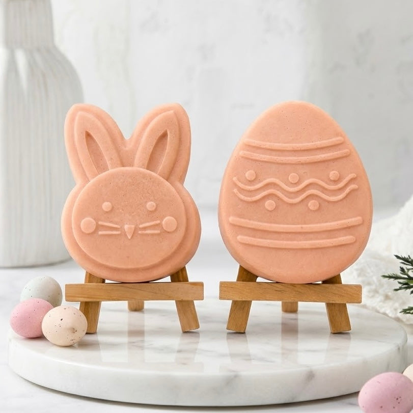 Handmade terracotta coloured Easter soap gift set for adults and kids. Two artisan vegan soaps, a cute bunny face and a patterned egg, stand on miniature wooden easels on a round marble tray with speckled miniature pastel eggs for decoration 