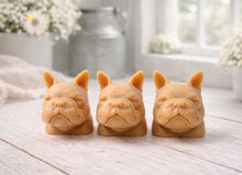 Load image into Gallery viewer, three french bulldog-head shaped bars of soap, side-by-side, on a wooden surface, set in a cozy, rustic bathroom with a vase of white and yellow flowers
