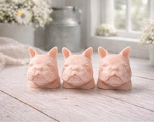 Load image into Gallery viewer, three french bulldog-head shaped bars of soap, side-by-side, on a wooden surface, set in a cozy, rustic bathroom with a vase of white and yellow flowers
