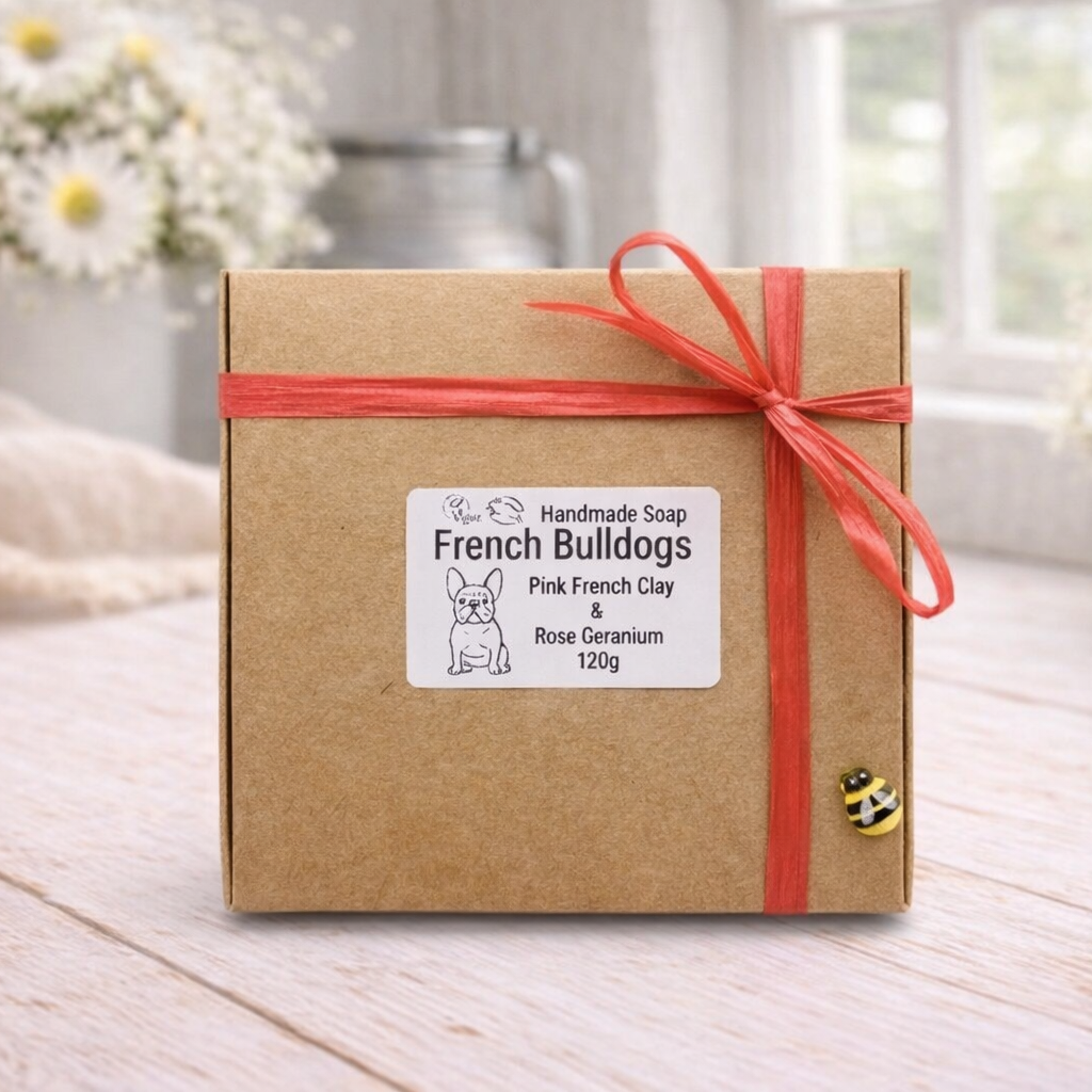 Gift box with a red ribbon on a wooden surface with blurred flowers in the background
