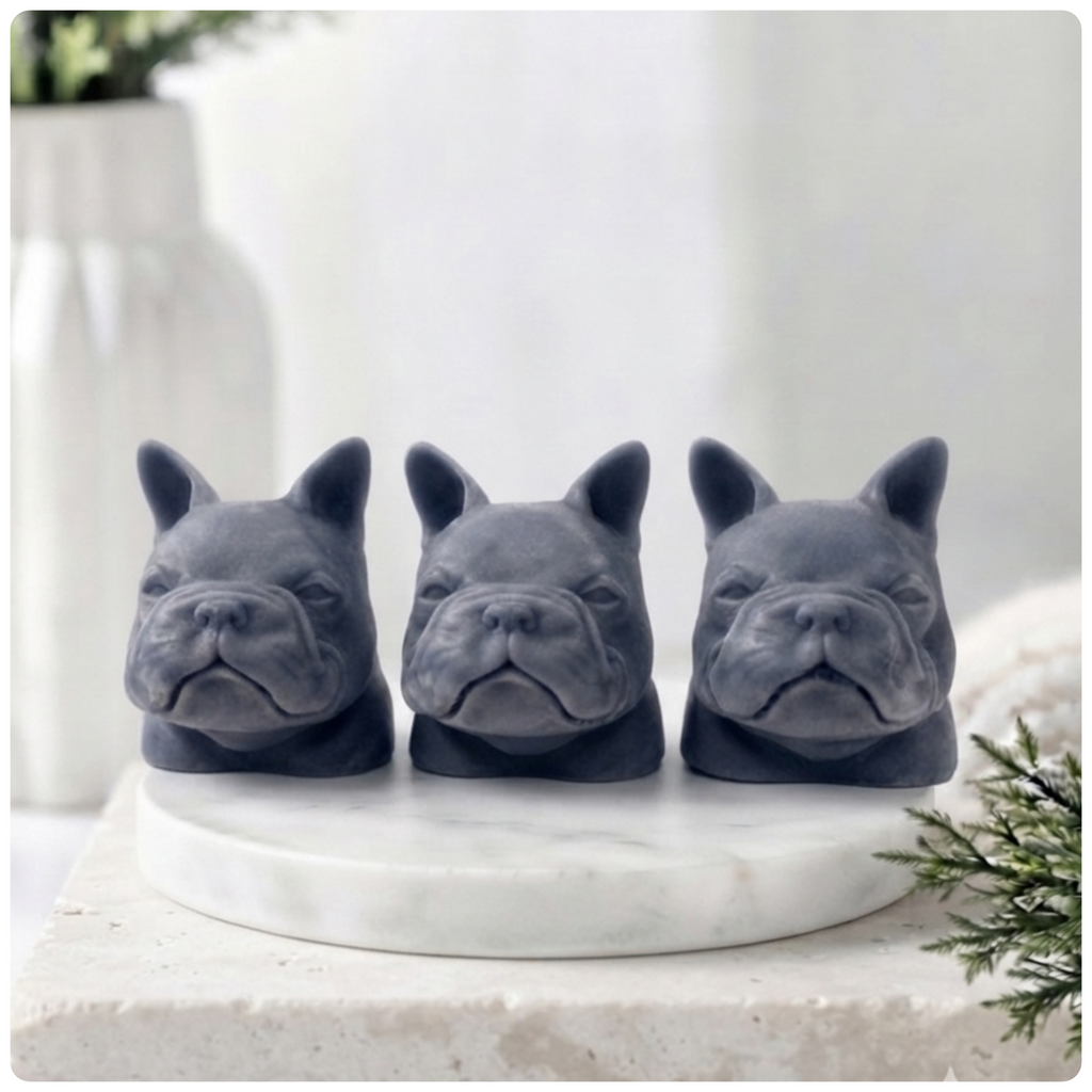 Three French bulldog-shaped soaps on a white surface with decorative elements.