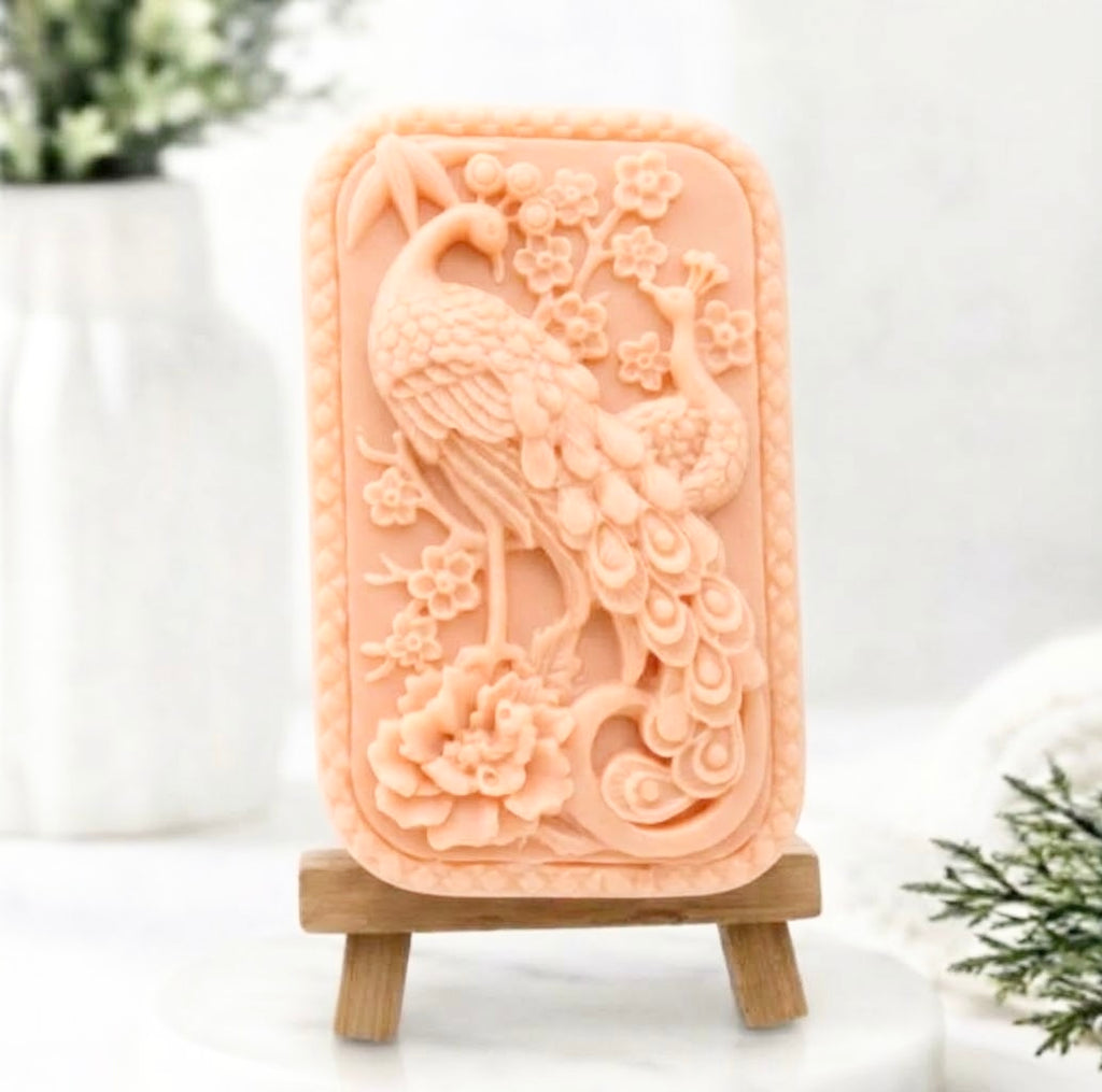 Pink French clay artisanal vegan soap with a relief of a peacock and cherry blossoms on a mini wooden easel. Gift idea