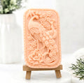 Pink French clay artisanal vegan soap with a relief of a peacock and cherry blossoms on a mini wooden easel. Gift idea