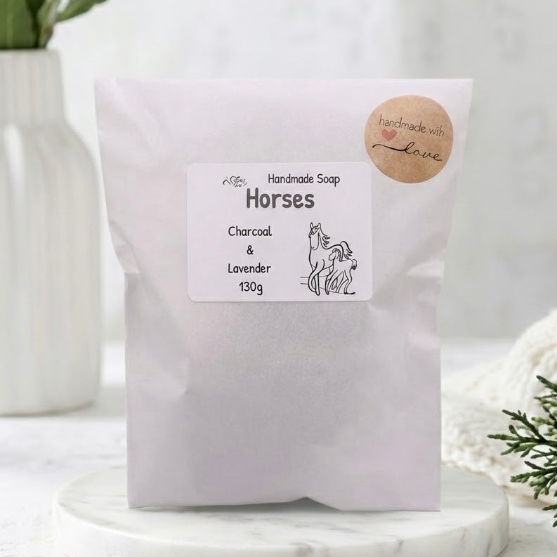 Product packaging for vegan 'Charcoal & Lavender' handmade horses soap, featuring a pink paper pouch, a 'Handmade Soap Horses' label with 130g and line art of mare and foal, and a round kraft paper sticker reading 'handmade with love' with a pink heart. Equestrian bath gift wrapping.