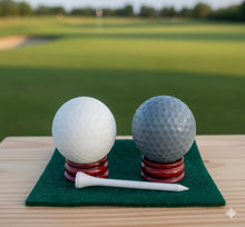 Load image into Gallery viewer, A set of two handmade vegan golf ball soaps in white and grey, displayed on miniature wooden stands with a golf tee in a bright farmhouse decor bathroom.
