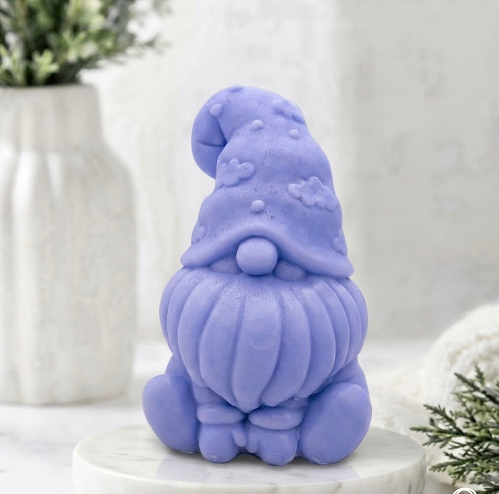 A handmade vegan soap in a blue tone, sculpted as a gnome (gonk) with a tall, curved hat that covers the eyes and has clouds on it, a round nose, and a long, textured beard.