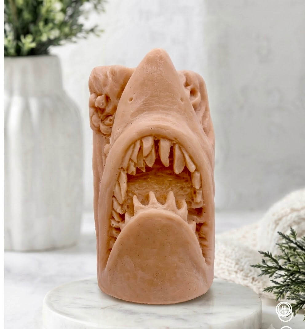 handmade shark soap made with red French clay and displayed on a wooden easel against a neutral background featuring a white vase and greenery.