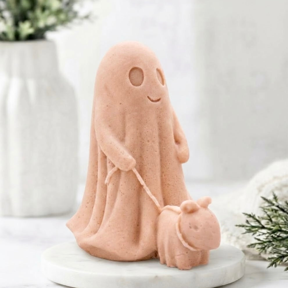 A soft pink decorative vegan soap figure of a ghost with a dog on a leash in a bright room with flowers.