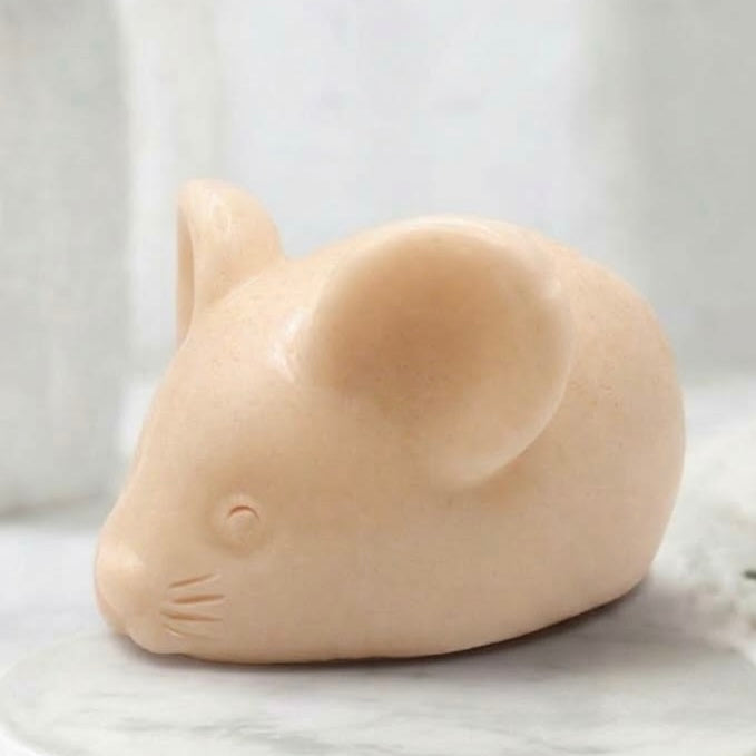 A soft yellow handmade vegan soap sculpted into the shape of a cute resting mouse with large rounded ears and a delicate snout