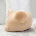 A soft yellow handmade vegan soap sculpted into the shape of a cute resting mouse with large rounded ears and a delicate snout