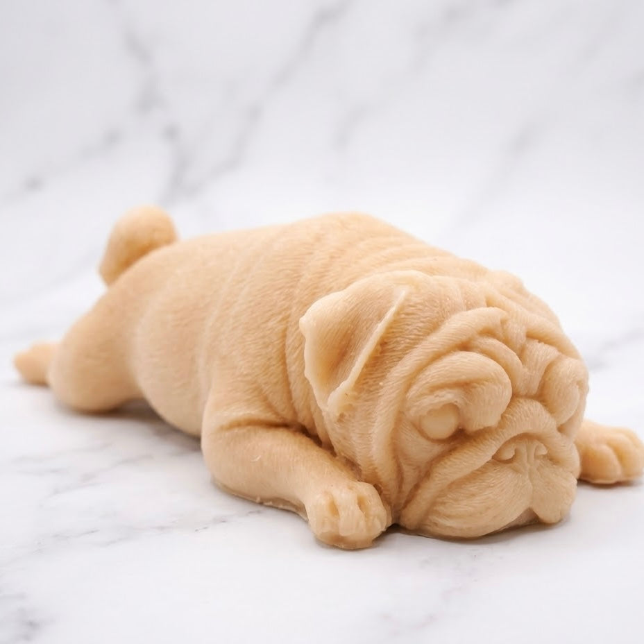 A yellow sleeping pug-shaped vegan soap gift. resting on a light marble surface with a soft background.