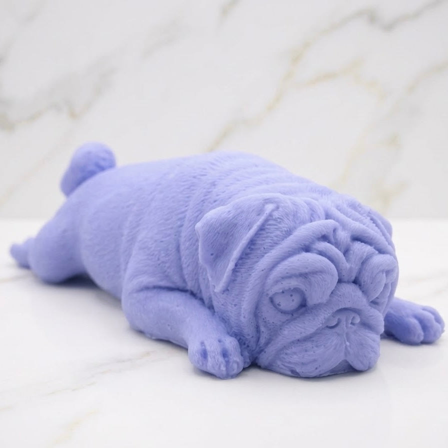 A soft blue pug-shaped vegan soap gift. resting on a light marble surface with a soft background.