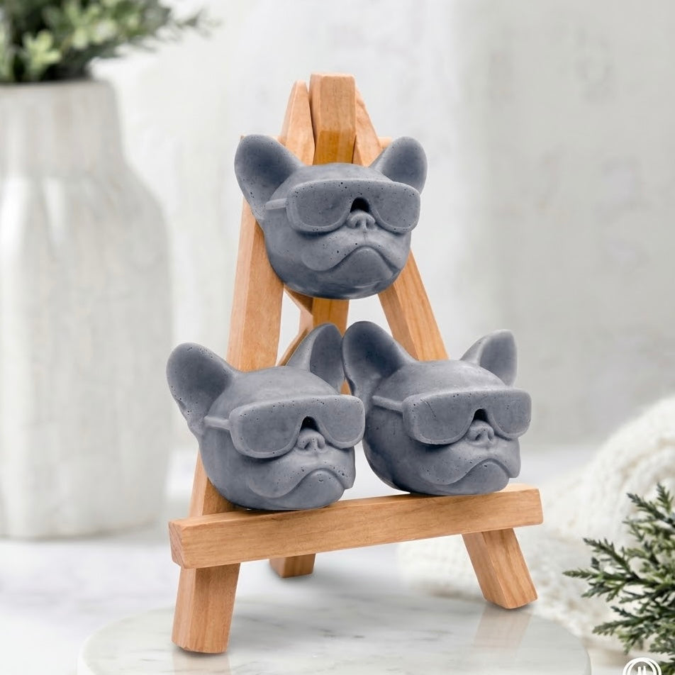 Artisan Frenchie novelty soap gift set, featuring three charcoal grey coloured dog-shaped soaps in sunglasses stacked on a wooden easel display stand. Handcrafted gift for French Bulldog lovers.