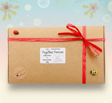 Load image into Gallery viewer, Two handcrafted vegan soaps, one in the shape of a couple embracing and another in the shape of a heart with 'I LOVE U' inscription, presented in a wooden display stand. Presented in beautiful eco friendly gift box with paper ribbon. 
