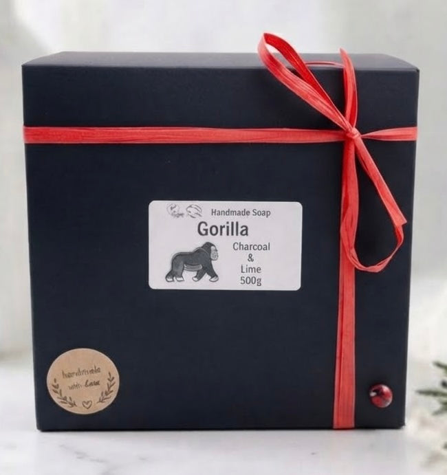 A black gift box for gorilla handcrafted soap, tied with a red ribbon and bow, featuring a white label that reads 'Gorilla Charcoal & Lime 500g'.