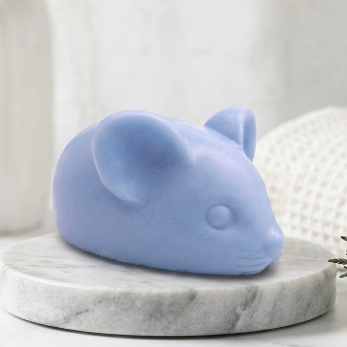 A soft blue handmade vegan soap sculpted into the shape of a cute resting mouse with large rounded ears and a delicate snout