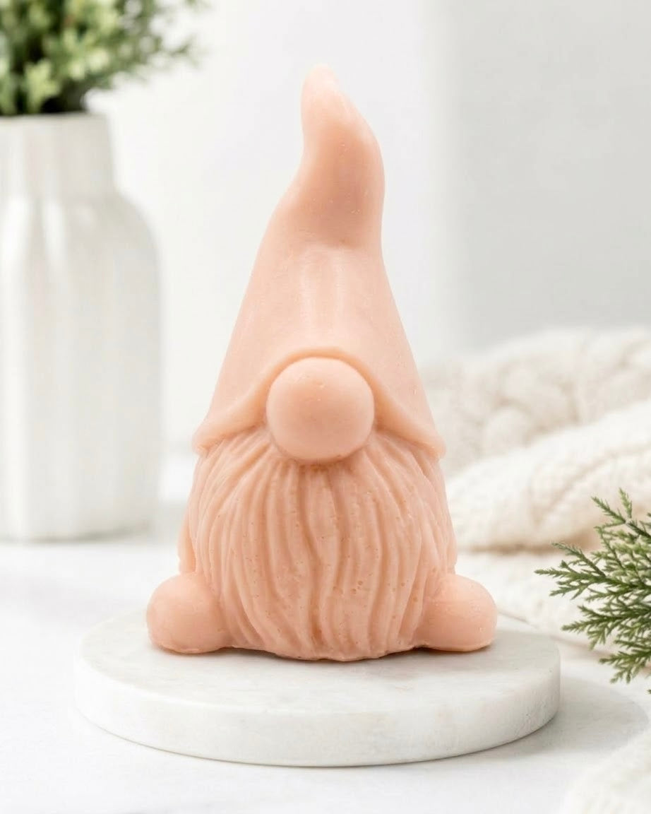 A soft-pink artisanal gnome vegan soap bar on a marble plinth, front view.
