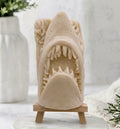 Front view of handmade shark soap made with yellow French clay and displayed on a wooden easel against a neutral background featuring a white vase and greenery.