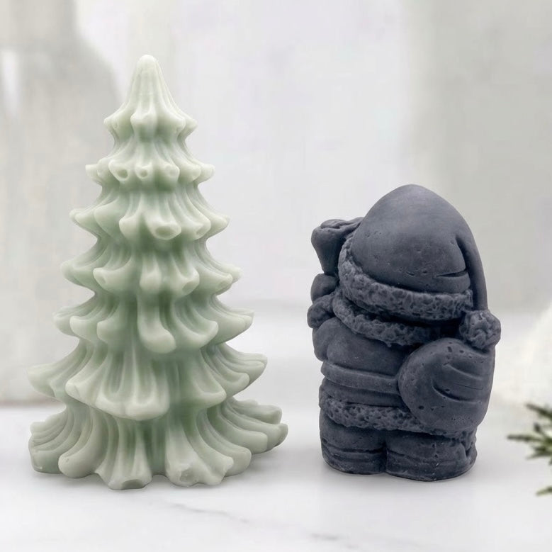 Handmade holiday soap gift set featuring a dark charcoal Santa figurine and a natural green Christmas Tree. Wrapped and ready for gifting.
