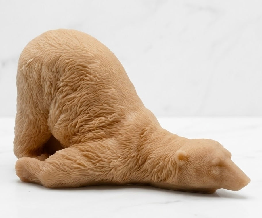 A terracotta coloured bar of soap sculpted into a lazy polar bear figure lying down on its side, set against a white marble background.