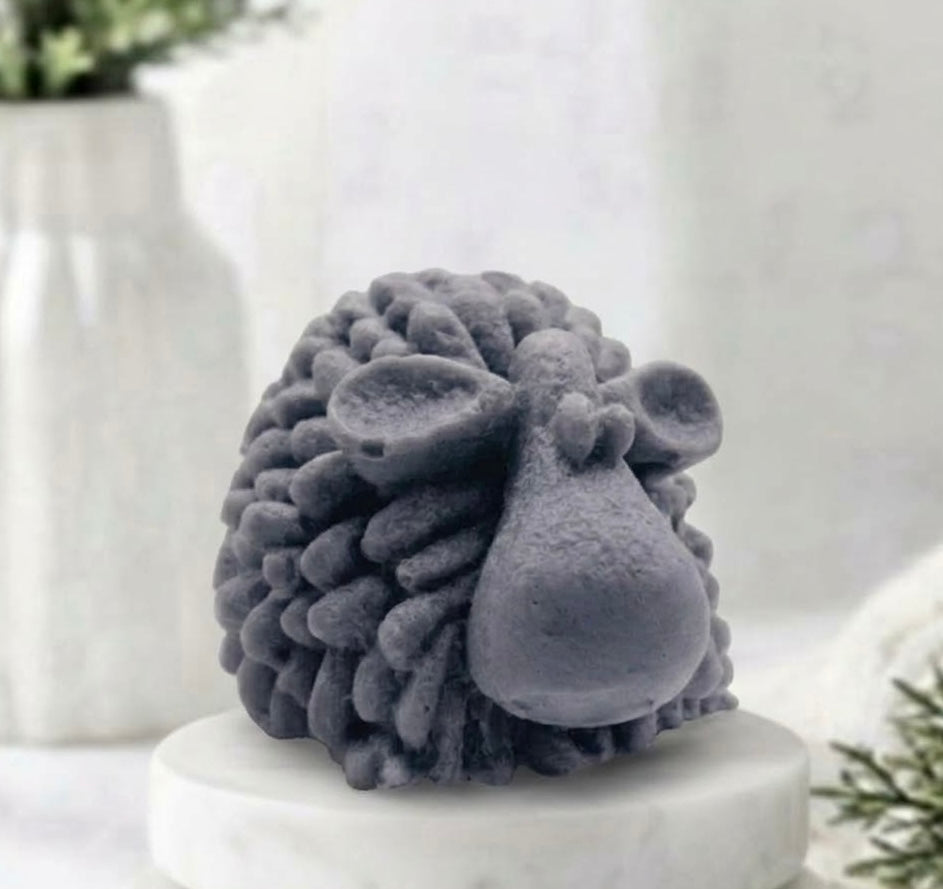 A highly detailed charcoal grey handmade vegan soap sculpted in the shape of a fluffy sheep with thick, textured wool and a smooth face