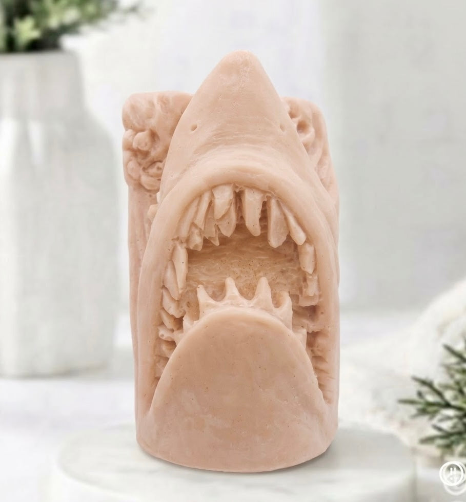 handmade shark soap with pink French clay displayed on a wooden easel against a neutral background featuring a white vase and greenery.