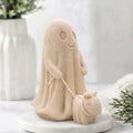 A soft yellow decorative vegan soap figure of a ghost with a dog on a leash in a bright room with flowers.