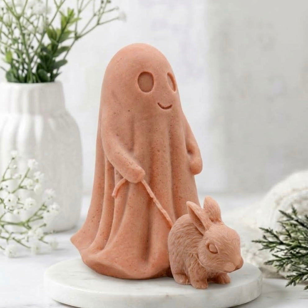 A terracotta decorative vegan soap figure of a ghost with a dog on a leash in a bright room with flowers.