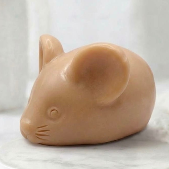 A terracotta handmade vegan soap sculpted into the shape of a cute resting mouse with large rounded ears and a delicate snout