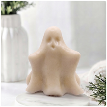 Load image into Gallery viewer, A handmade vegan soap shaped like a friendly ghost with a surprised expression, sitting on a light wood surface with white daisies in the background 
