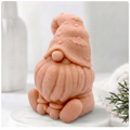 A handmade vegan soap in a natural tone, sculpted as a gnome (gonk) with a tall, curved hat that covers the eyes and has clouds on it, a round nose, and a long, textured beard.