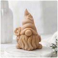 A 3D handmade vegan soap in a warm cream tone, sculpted into a cute garden gnome or gonk with a long flowing beard, a large round nose, and a tall pointed hat adorned with small embossed flowers.