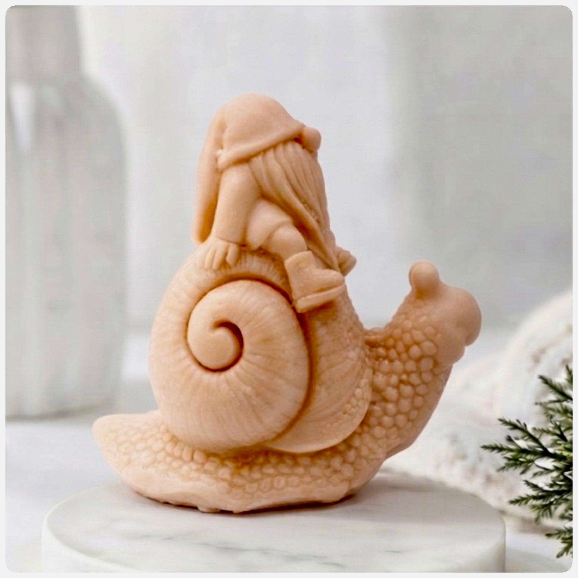 A handmade vegan soap gift, sculpted as a whimsical gnome (gonk) with a tall, slouchy hat and a long beard, sitting on the shell of a large snail with a textured, bumpy body.