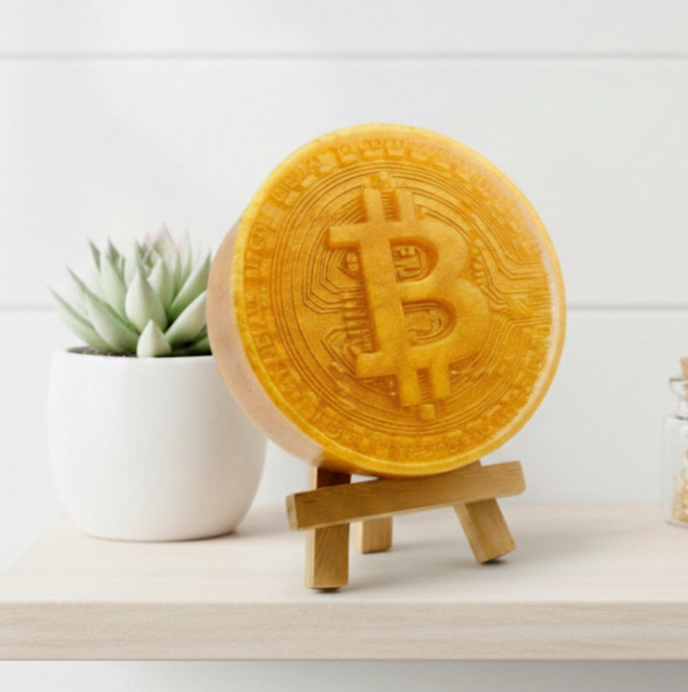 Golden Bitcoin-shaped vegan soap on a wooden stand with a white background