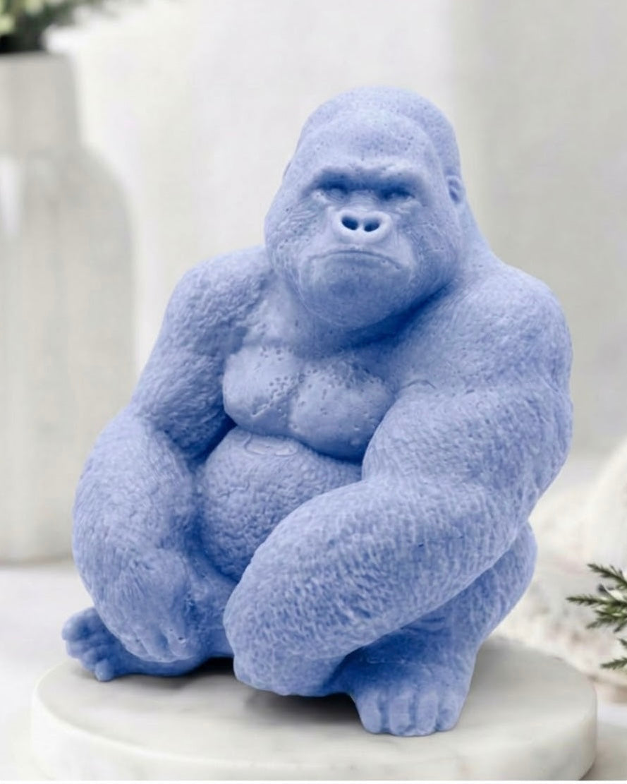 A large soft blue gorilla handmade soap sitting on a white marble base, photographed in a softly styled indoor setting with blurred decor in the background.