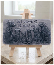 Load image into Gallery viewer, A rectangular handmade vegan soap bar gift, featuring a detailed relief carving of several dogs and a cat sitting together, with the words "all paws matter" and two paw prints embossed at the top, displayed on a wooden easel. Made in Blackpool.
