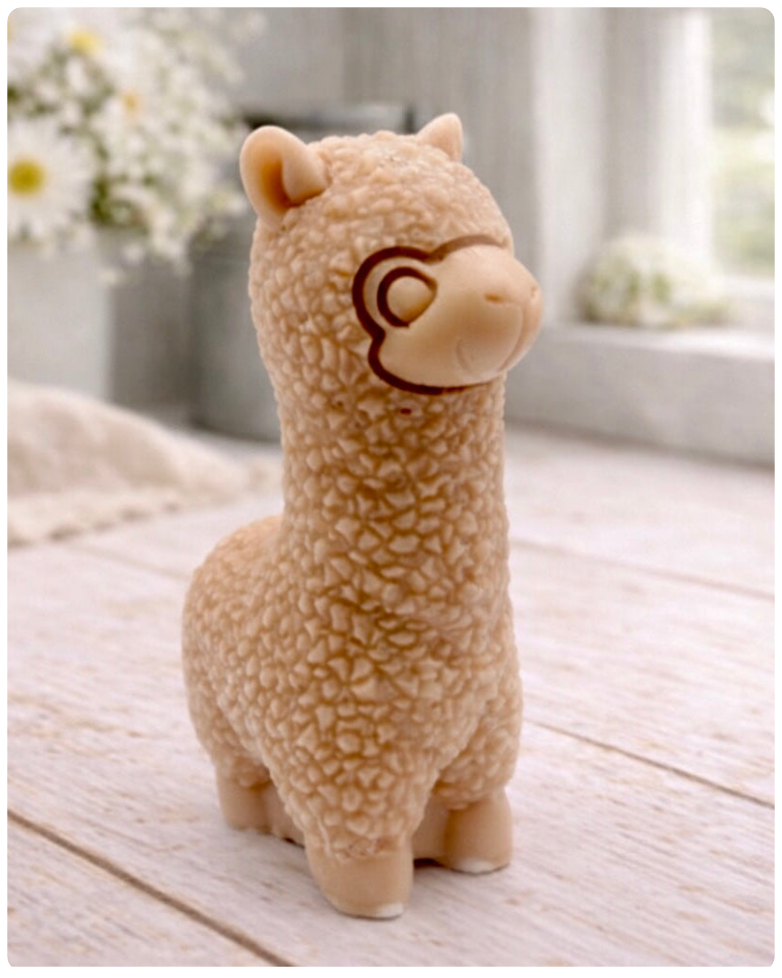handmade vegan soap in the shape of a realistic standing alpaca sculpture, featuring detailed curly wool texture and a smiling face, displayed on a rustic white wooden surface in a bright farmhouse decor setting.
