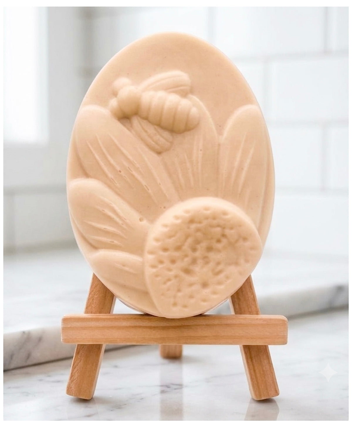 A handmade vegan soap in a natural colour, featuring an oval relief of a honeybee landing on a large sunflower with detailed petals and a textured centre, displayed on a small wooden easel.