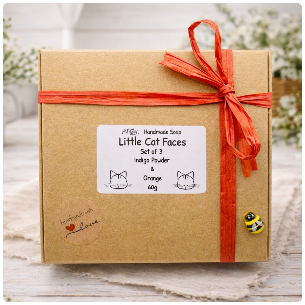 Box of handmade soap with a red ribbon and 'Little Cat Faces' label on a wooden surface.