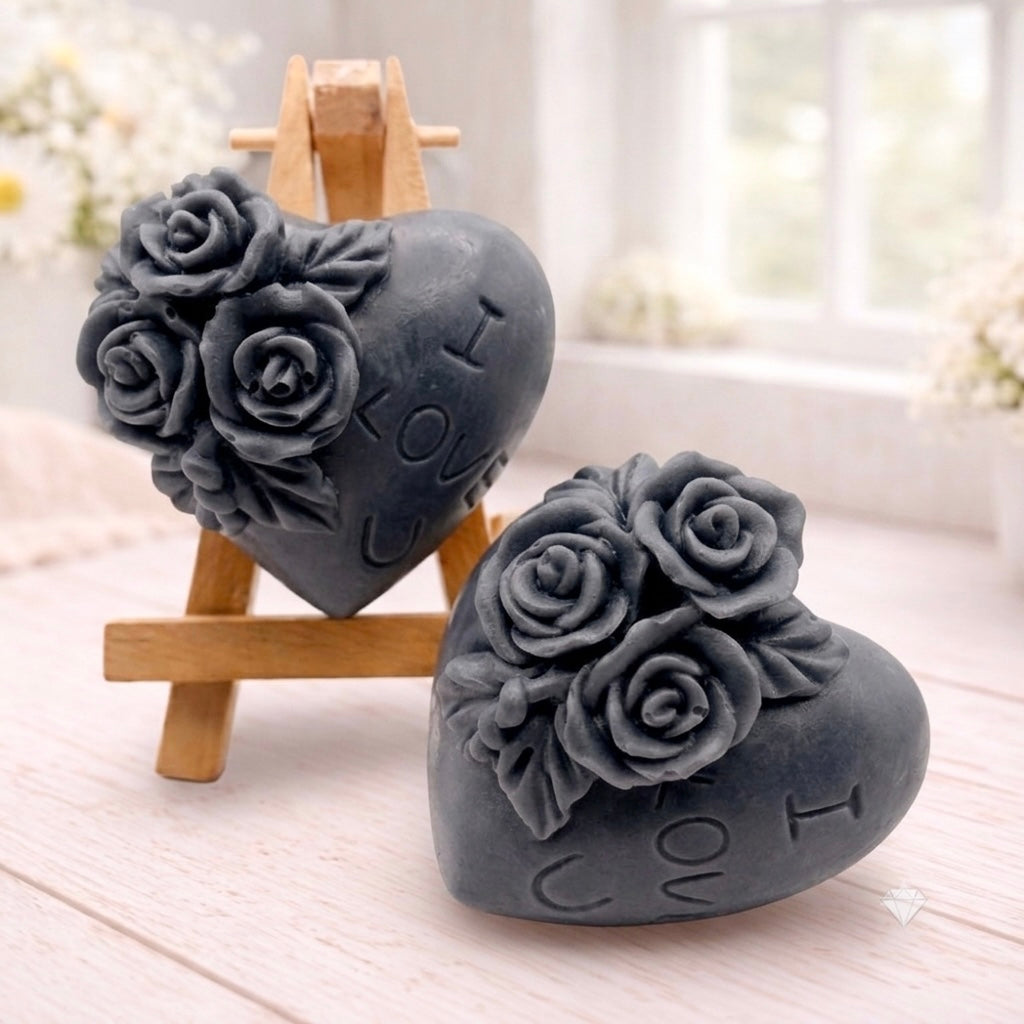 A handmade vegan soap gift set, featuring a central heart-shaped relief surrounded by a border of intricate rose flowers and delicate foliage, displayed on a small wooden easel.