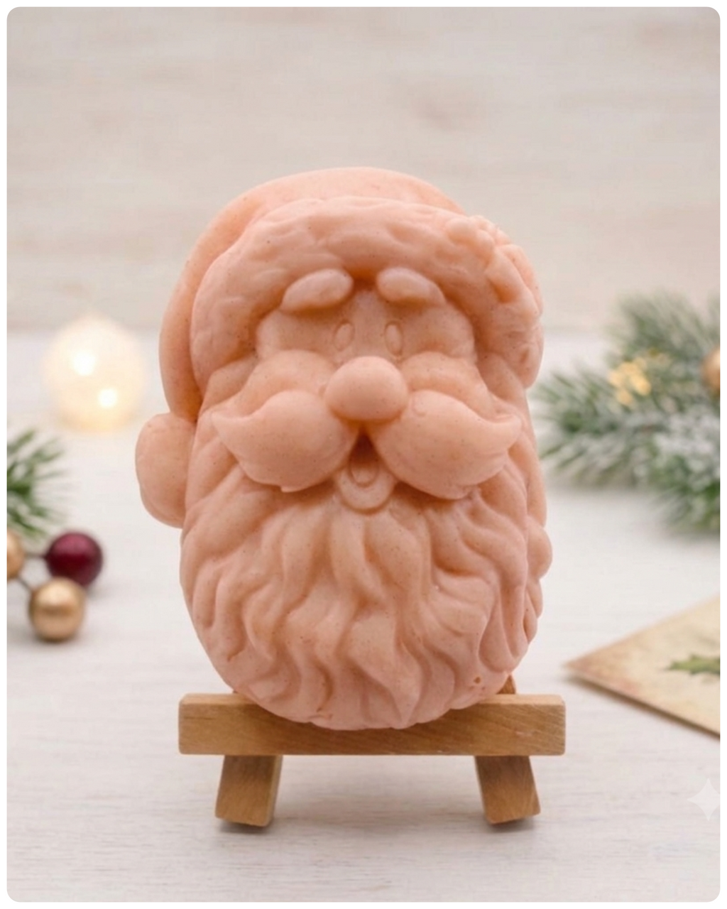 handmade vegan soap sculpted in the shape of Father Christmas's head, featuring a detailed curly beard, a jolly moustache, and a classic Santa hat, displayed on a miniature wooden easel in a bright farmhouse setting.