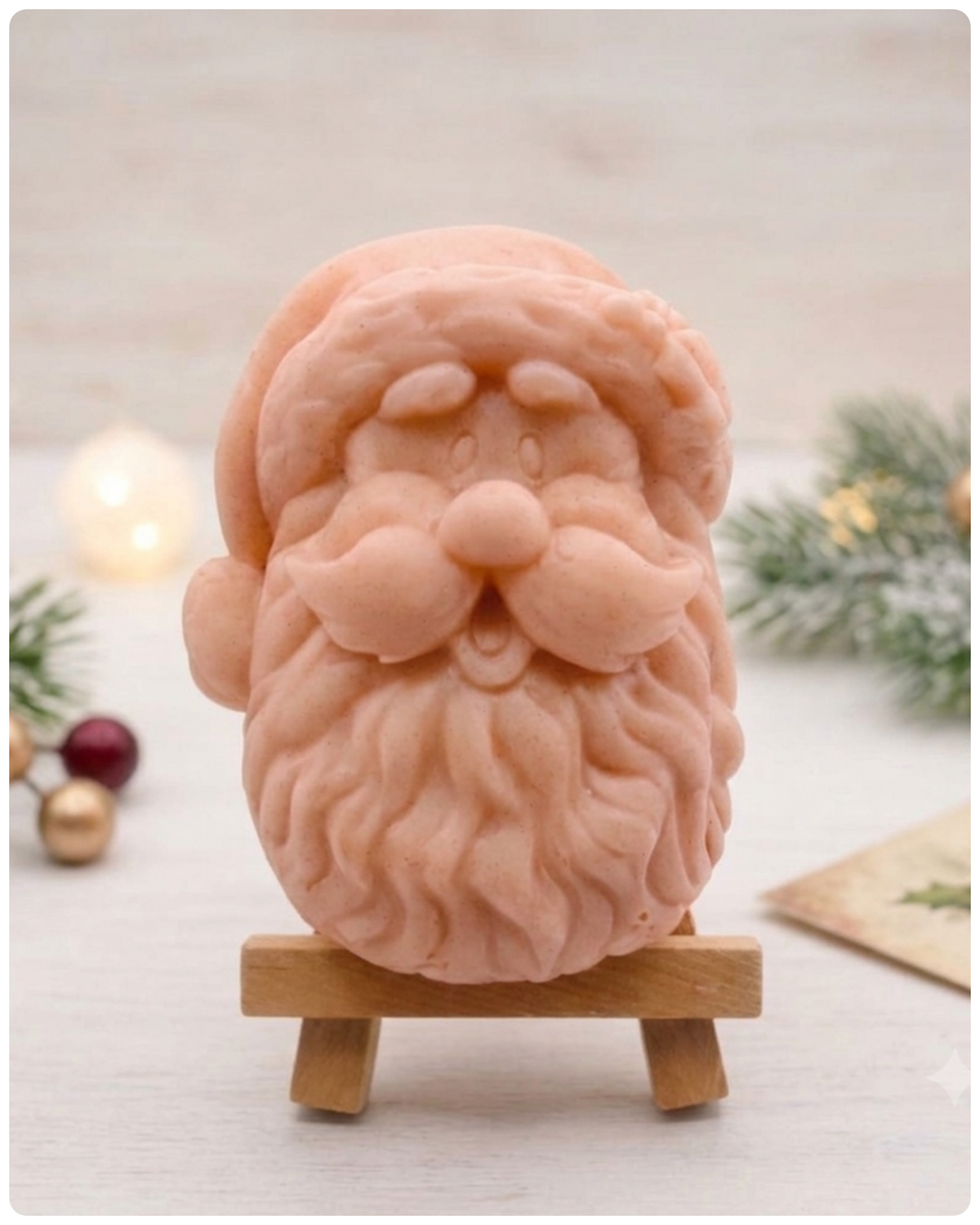 handmade vegan soap sculpted in the shape of Father Christmas's head, featuring a detailed curly beard, a jolly moustache, and a classic Santa hat, displayed on a miniature wooden easel in a bright farmhouse setting.