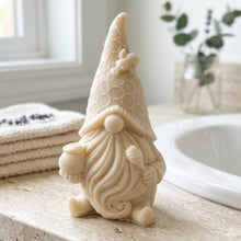 Load image into Gallery viewer, A handmade vegan soap in the shape of a gnome with a long beard, wearing a honeycomb-patterned hat with a bee, holding a honey pot and dipper.
