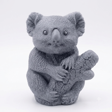Load image into Gallery viewer, A highly detailed handmade vegan soap in a sculpted in the shape of a realistic koala bear sitting upright and clutching a textured eucalyptus branch

