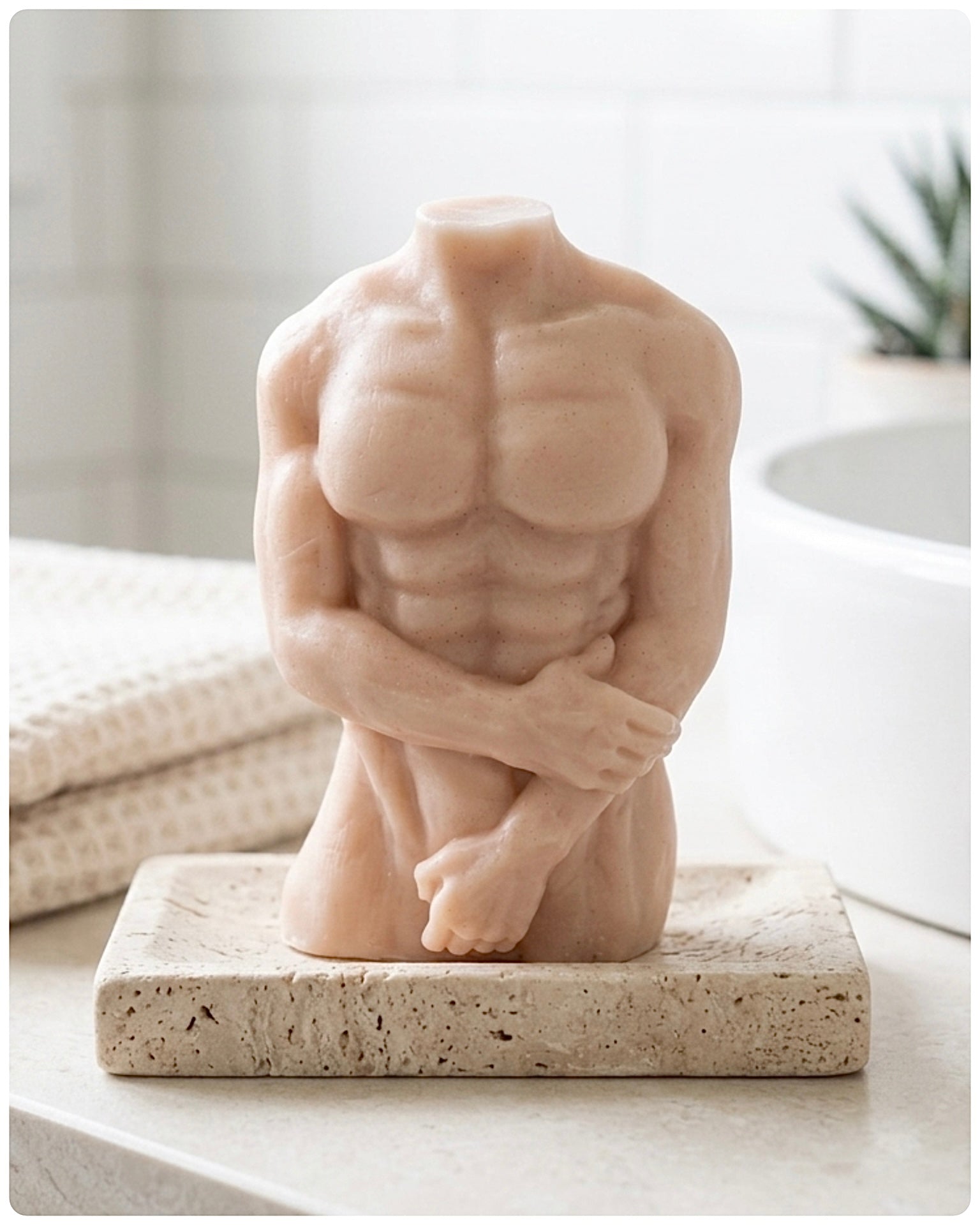 A 3D handmade vegan soap sculpted into a detailed male torso with defined chest and abdominal muscles, finished in a soft tone and displayed in a bright farmhouse setting.