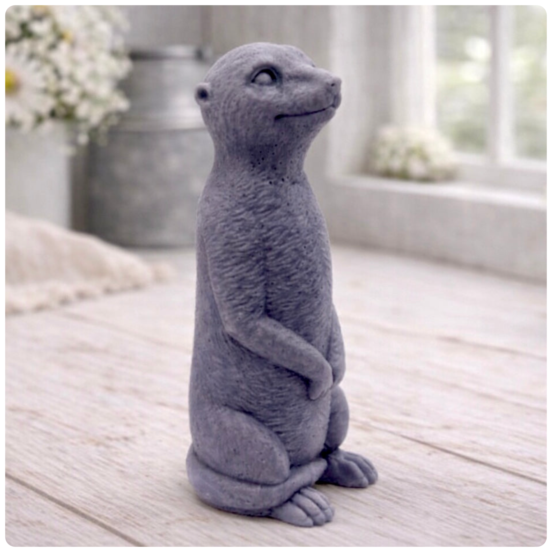 A highly detailed handmade vegan soap, sculpted in the shape of a realistic meerkat standing upright in its iconic sentinel pose, featuring textured fur and a curious facial expression, displayed on a light wooden surface.